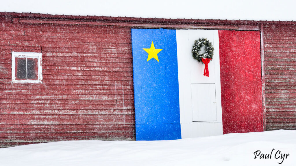 Wreath on a barn door painted as the Acadian flag